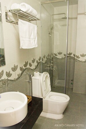 A bathroom with a glass-enclosed shower, a toilet, and a sink. - An Hoi Canary Hotel (Da Nang)