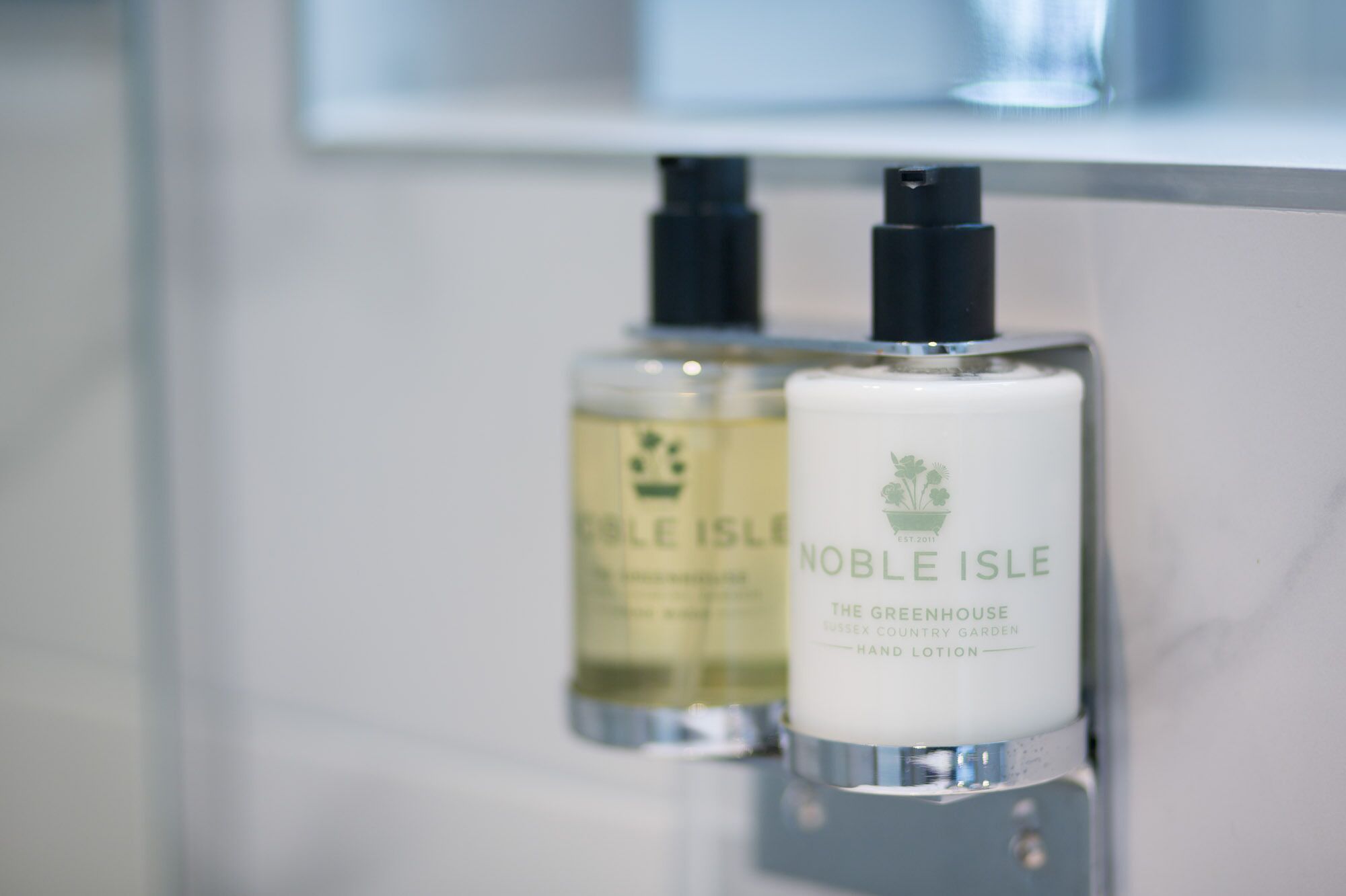 Dos botellas de loción para manos sobre una repisa de baño.