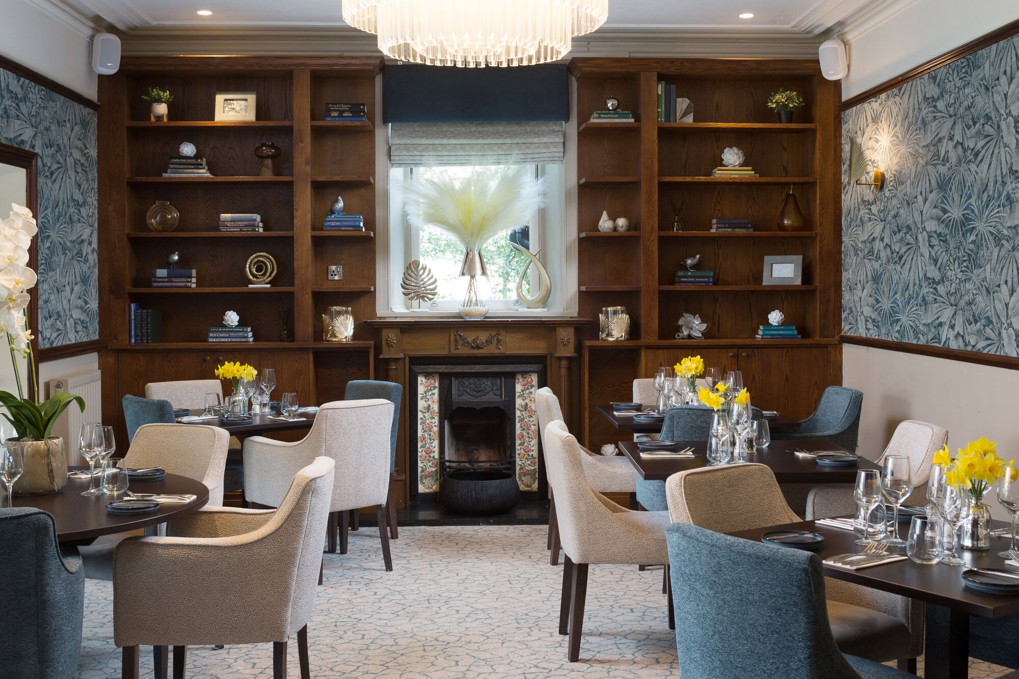 A dining area with a fireplace, wooden bookshelves, and a view of the outdoors through a window.