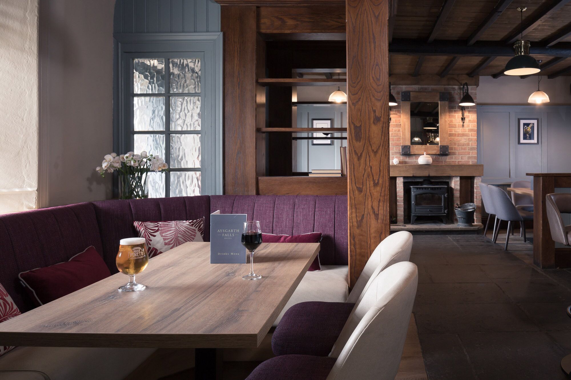 Un restaurante con mesa de madera y asientos tipo banqueta tapizados en morado.