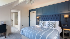 A bedroom with a large bed, a nightstand, a desk, and a chair. - Aysgarth Falls Hotel (Leyburn)