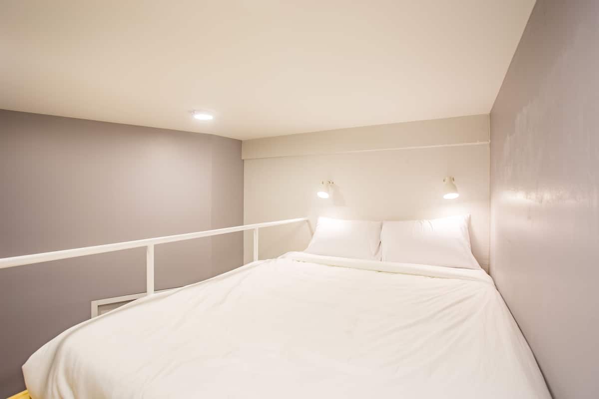 A bedroom with a bed, white headboard, and bedside lamps.