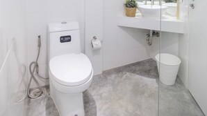 A modern bathroom with a toilet, sink, and mirror. - Nornyaowarat Hostel (Bangkok)