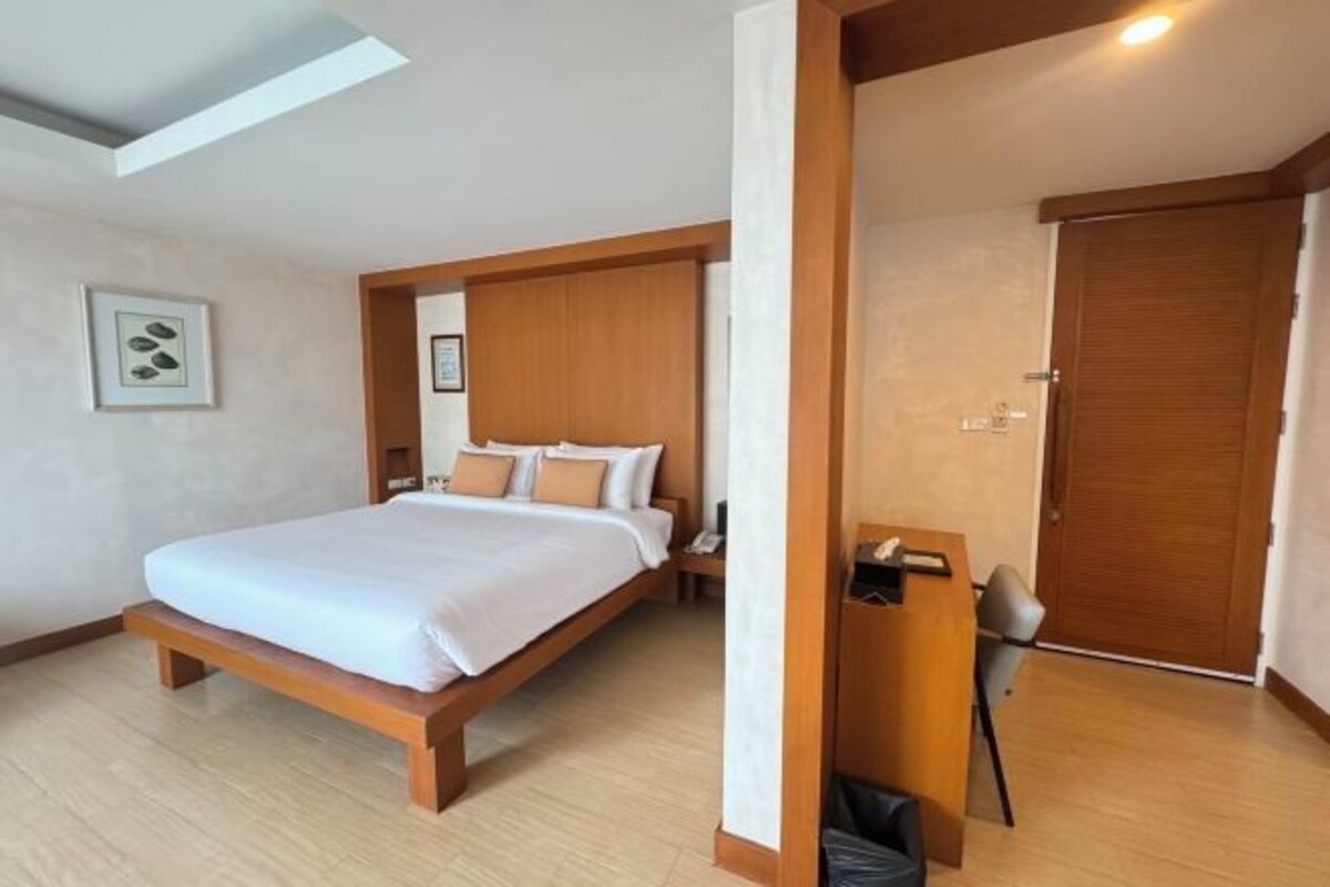Een hotelkamer met een houten bed, een bureau en een deur.