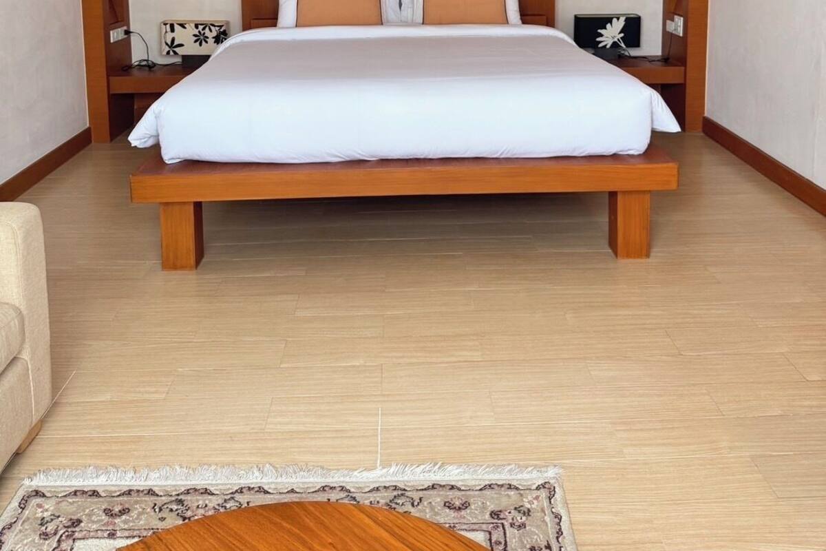 Une chambre moderne avec un grand lit, une tête de lit en bois et un luminaire au plafond.
