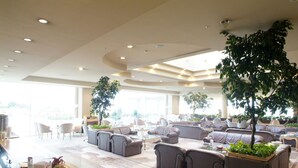 A spacious lobby with multiple seating areas, a coffee table, and a reception desk. - Hotel Juraku (Ito)