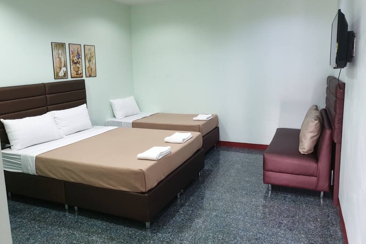 A hotel room with two beds, a sofa, and artwork on the wall.