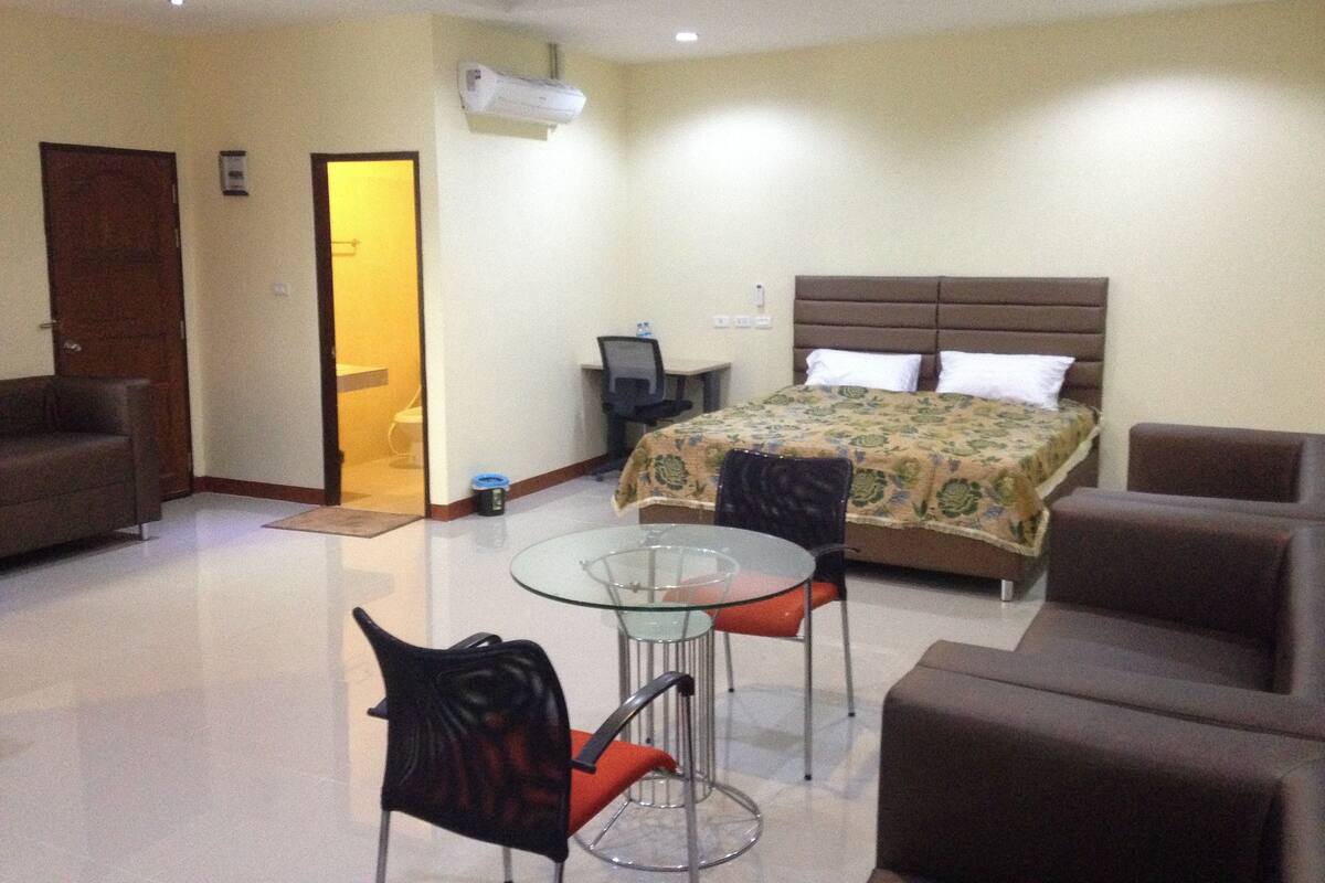 A hotel room with a bed, a desk, a chair, and a couch.