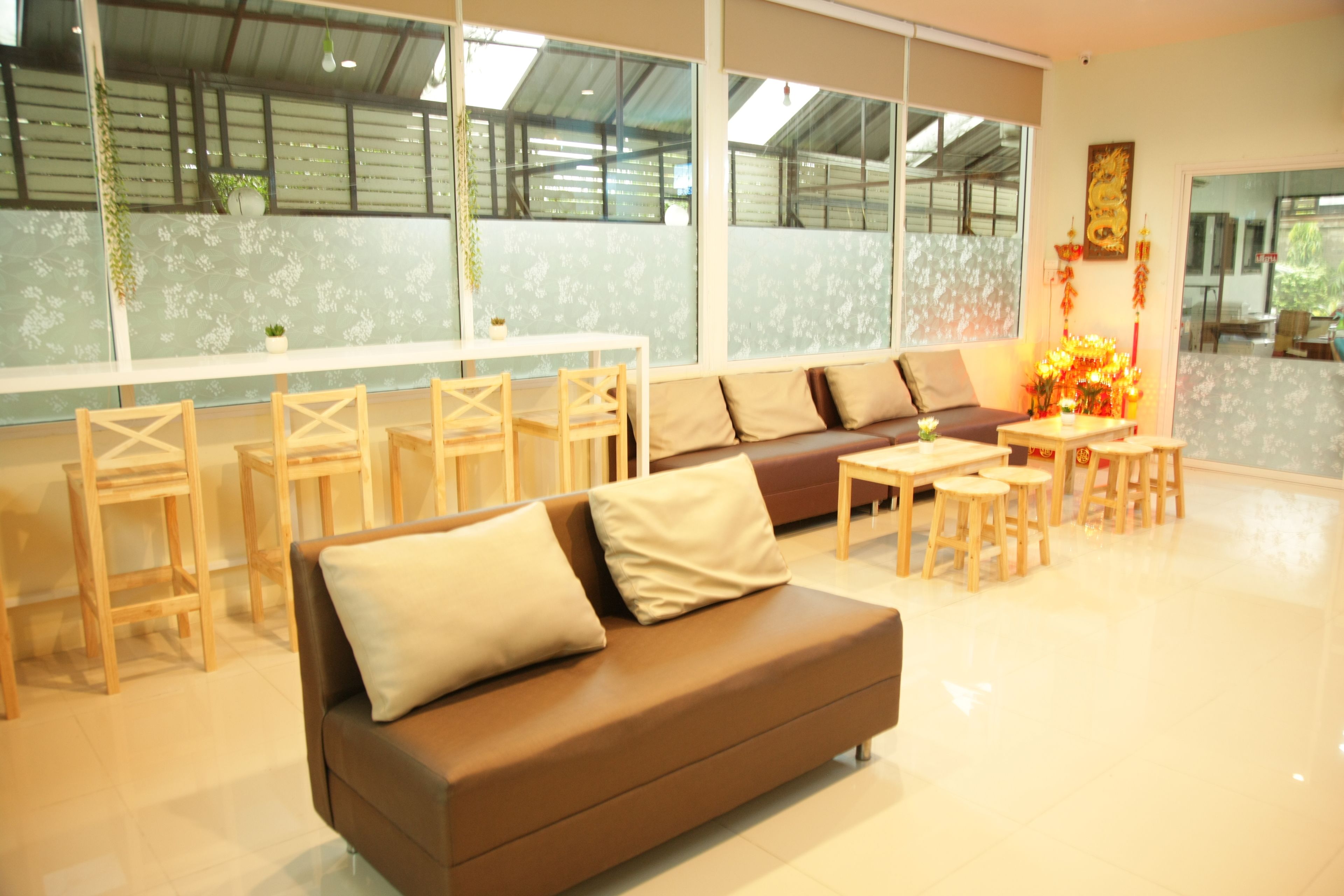 A modern living room with a brown sofa, wooden chairs, a coffee table, and a decorative plant.