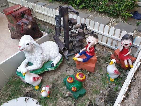 A garden with various sculptures, including a white sheep, a child, and a duck. - Friend's House Resort (Bangkok)