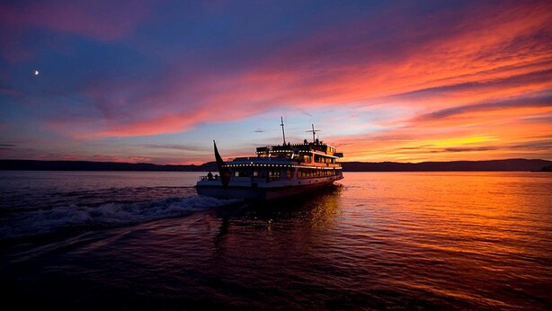 A boat on a body of water during sunset with a colorful sky. - Hotel Mozart Rorschach (Rorschach)