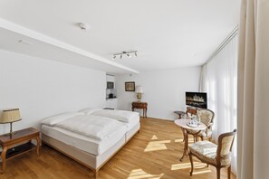 A hotel room with a bed, a desk, a chair, a television, and a window with curtains.