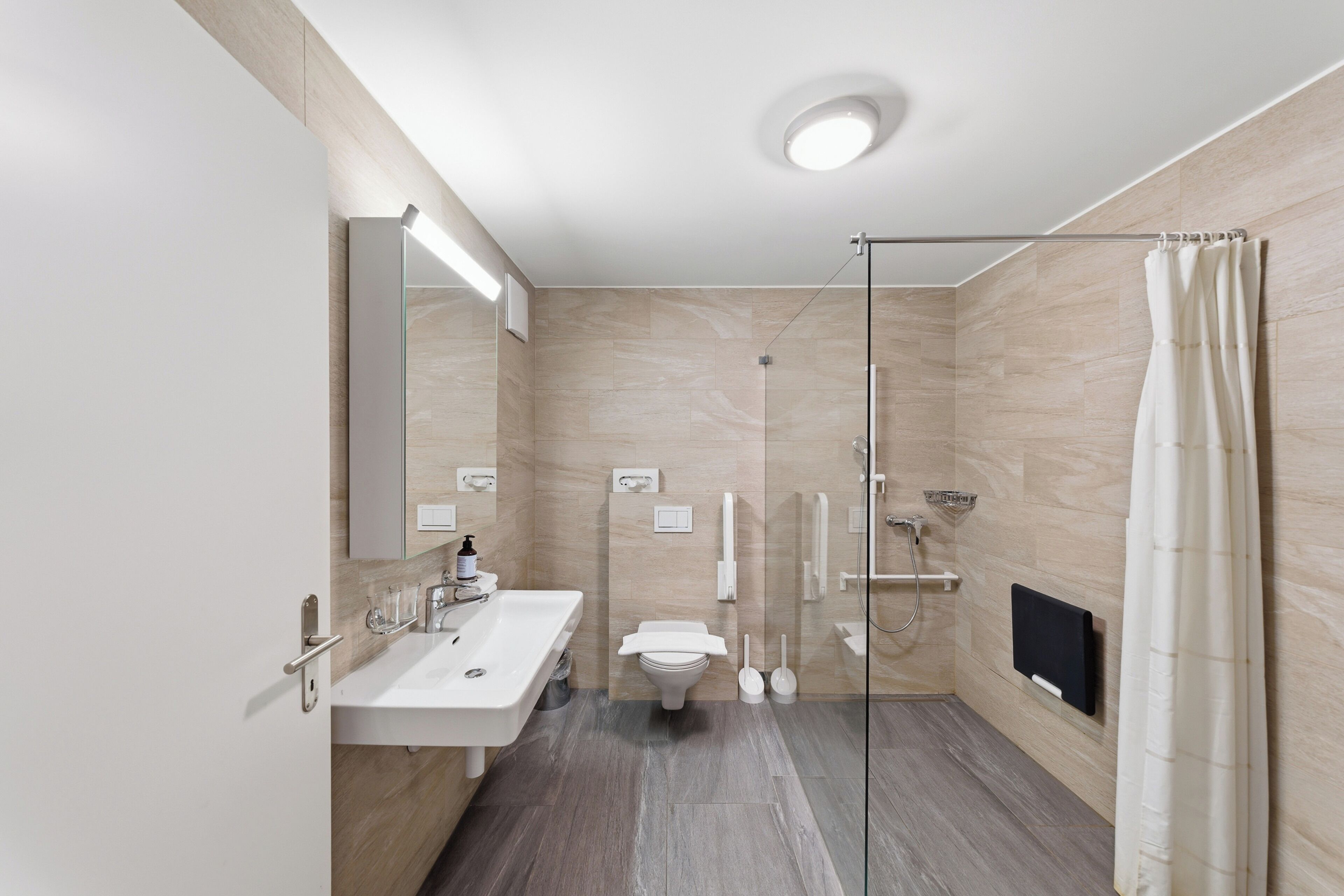 Un baño moderno con cabina de ducha de vidrio, lavamanos doble e inodoro.