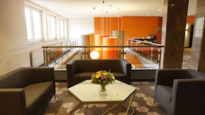 A modern lobby with a glass coffee table, two sofas, and a vase of flowers. - Trans World Hotel Auefeld (Hann. Muenden)