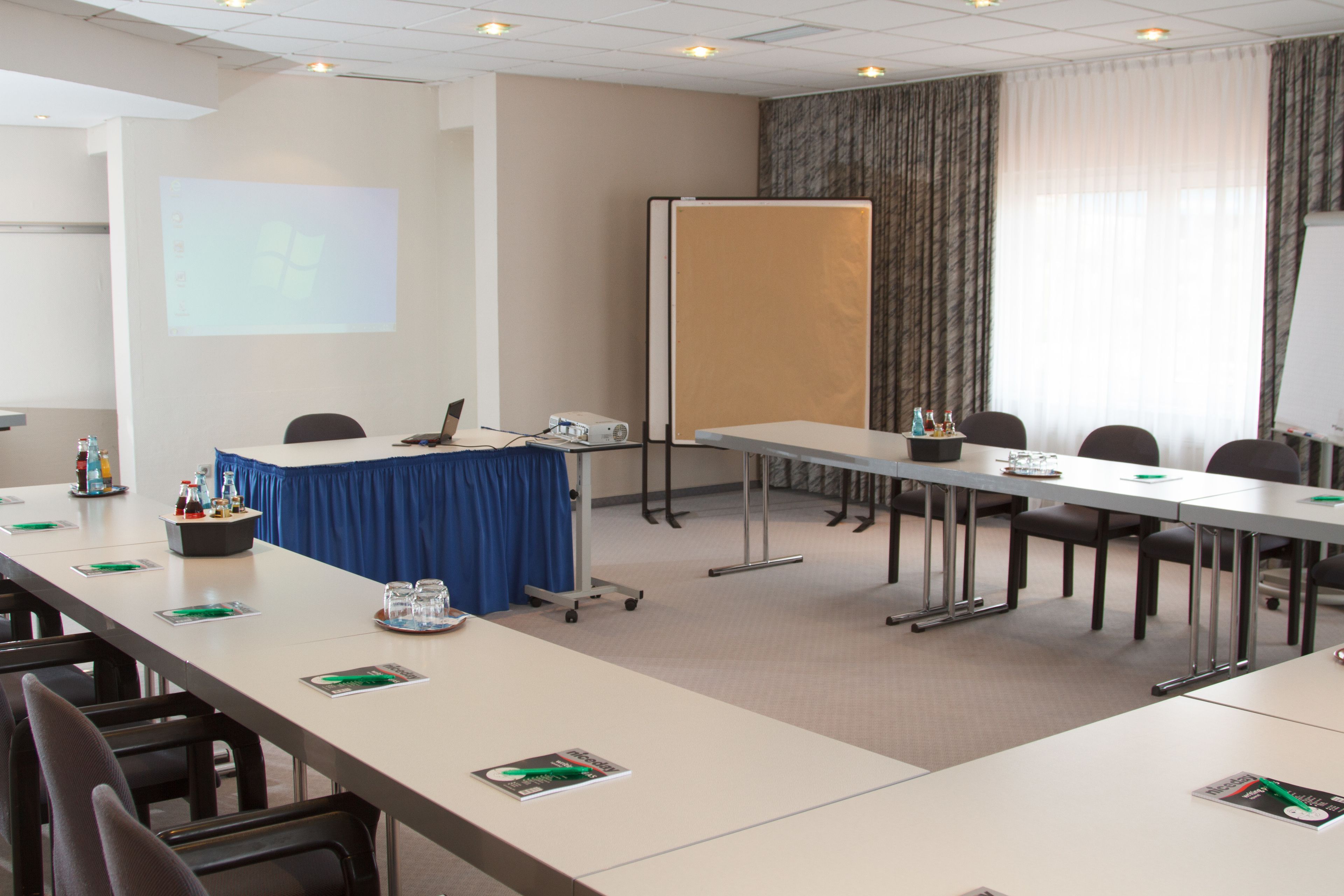 A conference room with a long table, chairs, a projector screen, and a whiteboard.