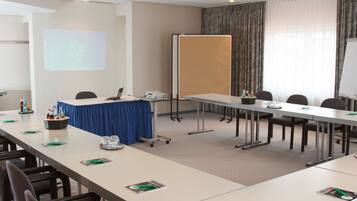 A conference room with a long table, chairs, a projector screen, and a whiteboard.