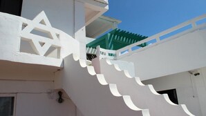 A white building with a staircase leading to a balcony. - GMG Hotel (Coron)