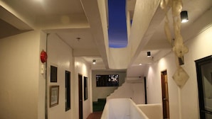 A hallway with a staircase leading to an upper level, white walls, and a blue accent wall. - GMG Hotel (Coron)
