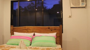 A bedroom with a wooden headboard, two pillows, and a window. - GMG Hotel (Coron)