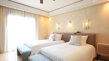 Een hotelkamer met twee bedden, een plafondventilator en bedlampjes.