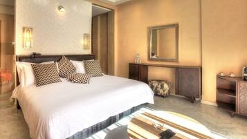 Una habitación de hotel con una cama grande, una mesita de madera, un espejo y un armario pequeño.