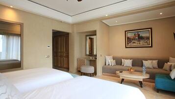 A hotel room with two beds, a sofa, a coffee table, and a ceiling fan.