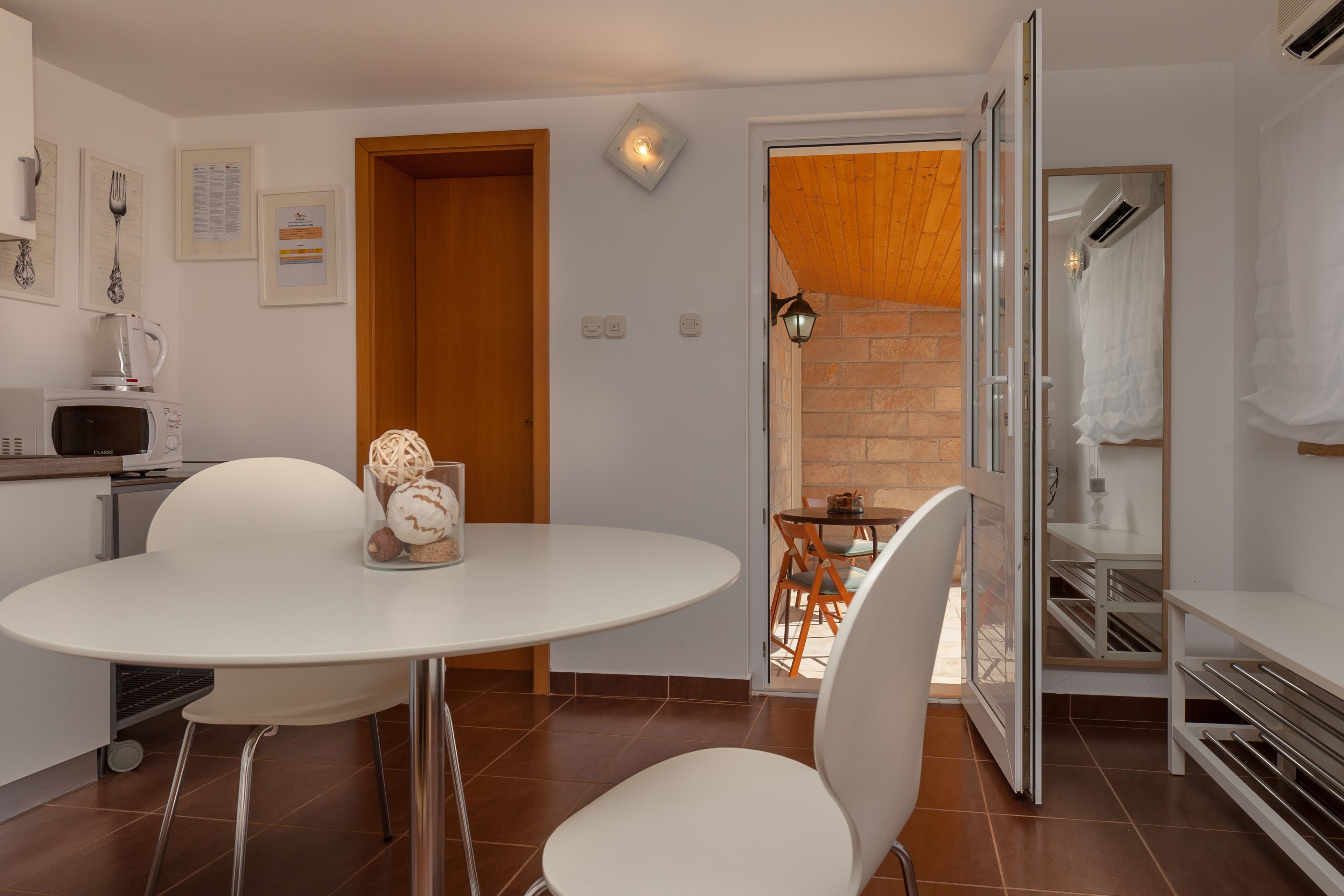 Une cuisine moderne avec des appareils électroménagers blancs, une table à manger ronde et un mur en briques.