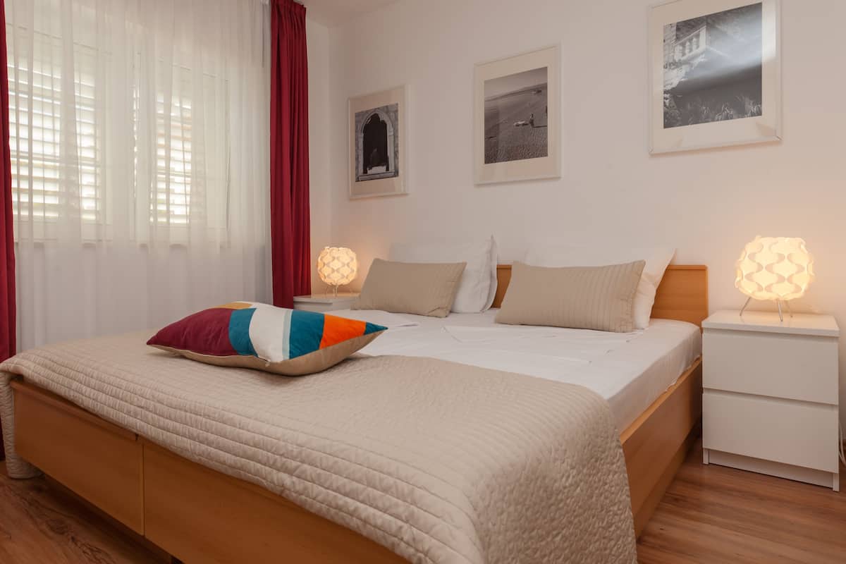 A neatly arranged bedroom with a bed, bedside tables, and wall-mounted artwork.