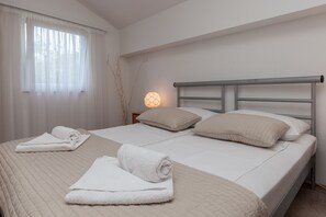 Un lit double avec une tête de lit, deux oreillers et des serviettes enroulées posées sur le lit.