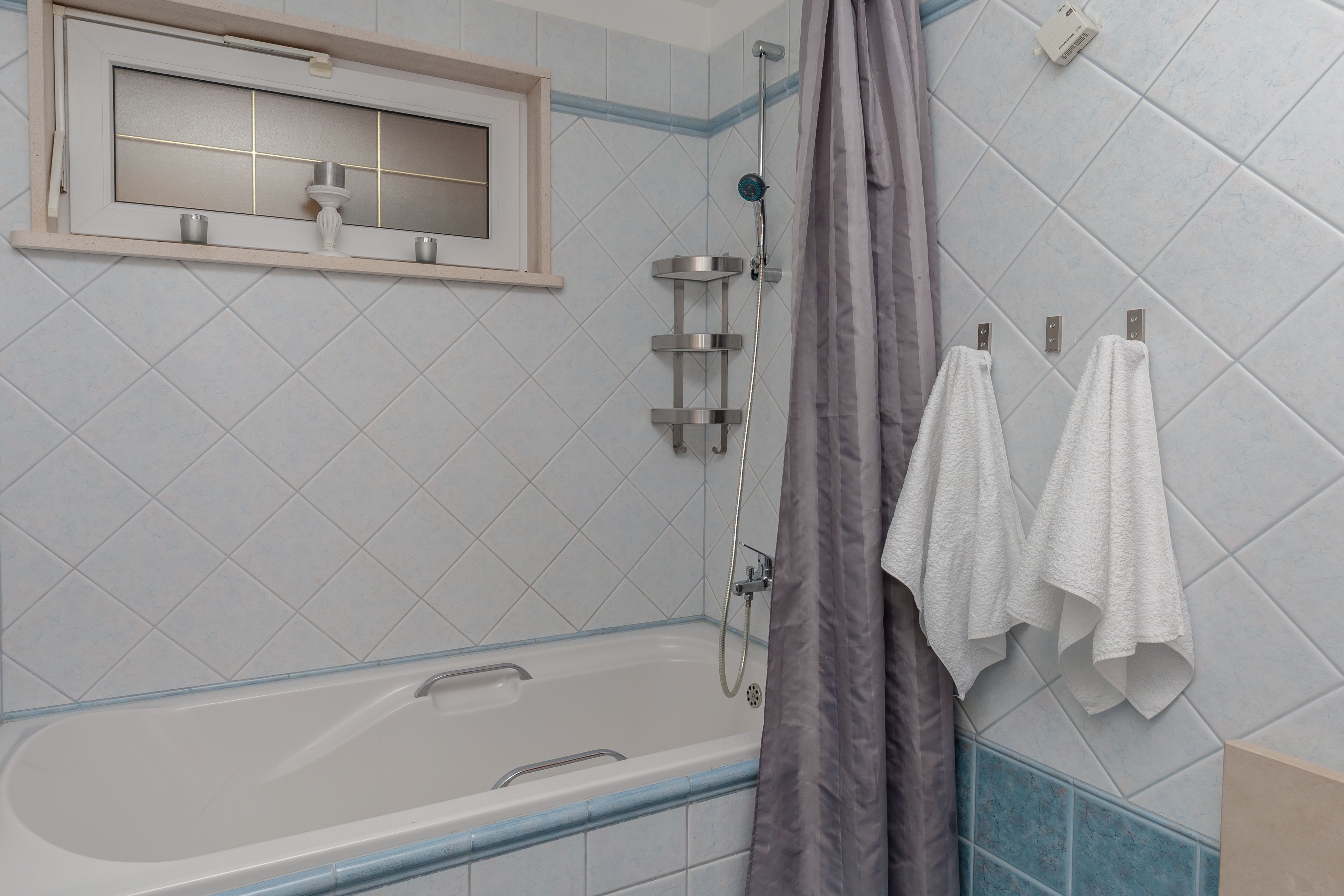 Een badkamer met een bad, een douche en een spiegel met plank.
