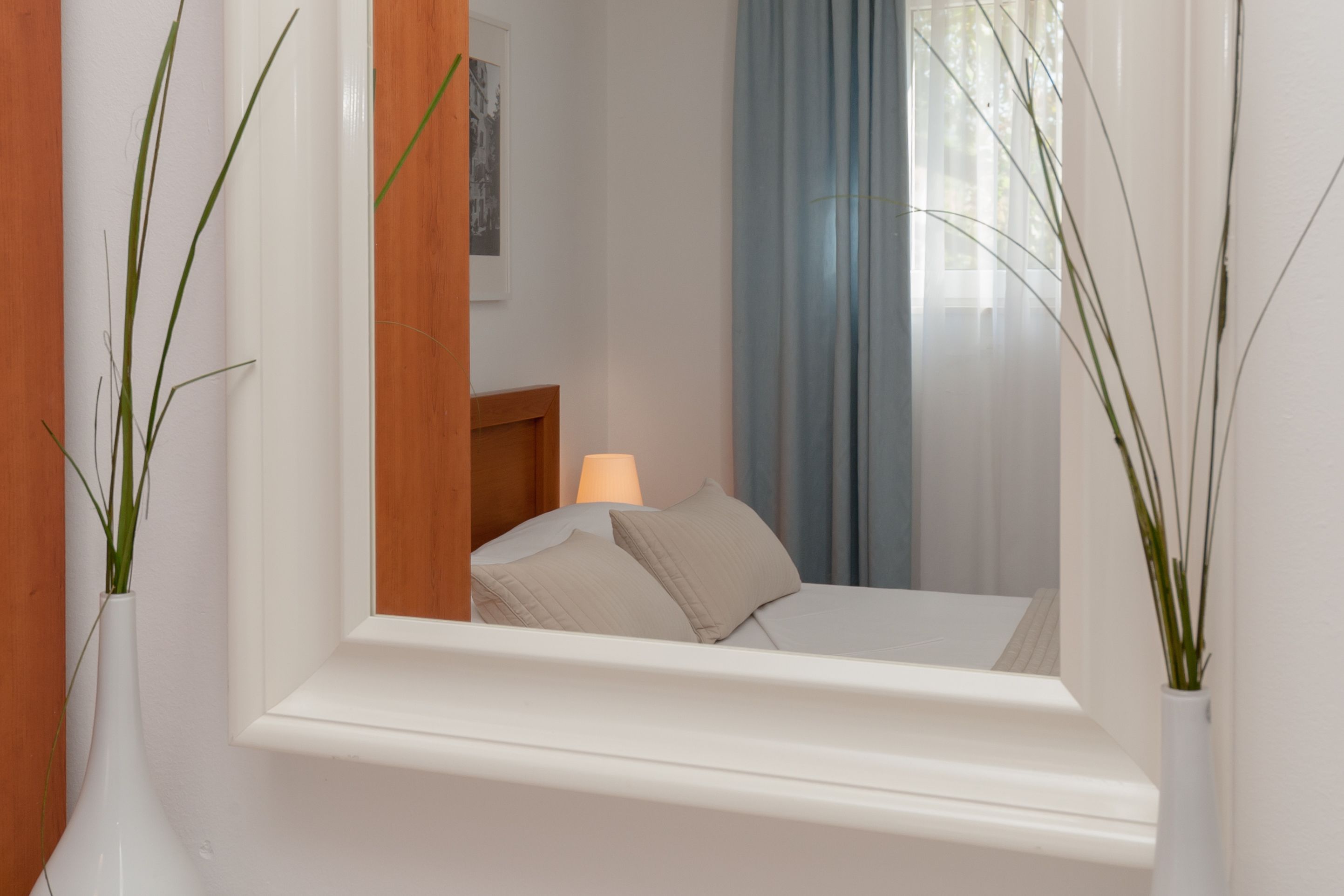 A bedroom with a bed, a nightstand, a lamp, and a window with curtains.