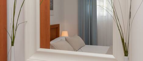 A bedroom with a bed, a nightstand, a lamp, and a window with curtains.