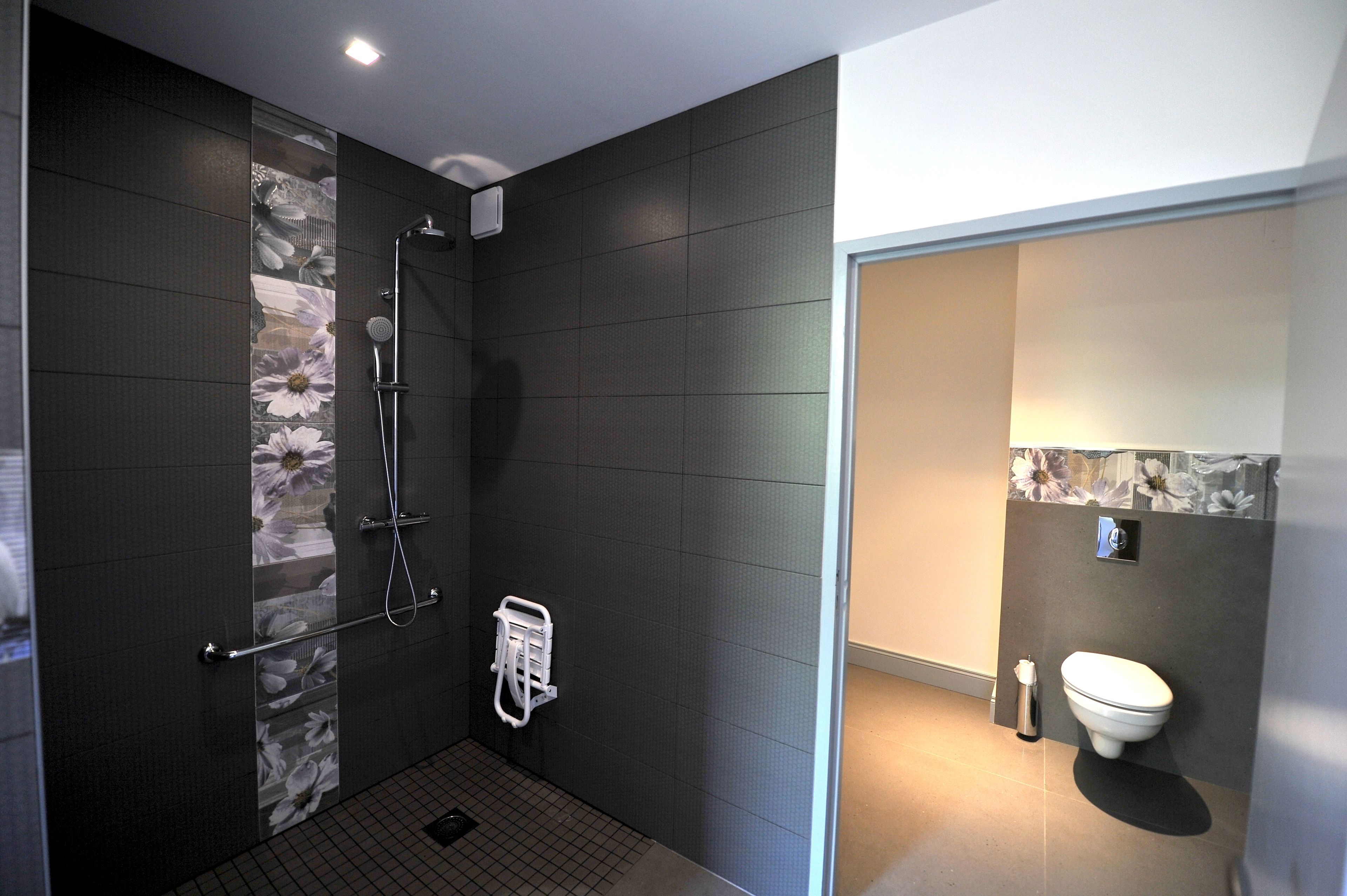 Un baño moderno con ducha, inodoro y toallero.
