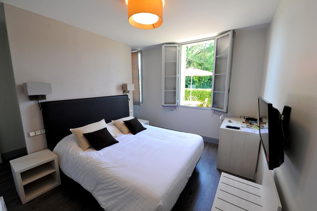 Une chambre moderne avec un grand lit, des tables de chevet, un bureau et un téléviseur.