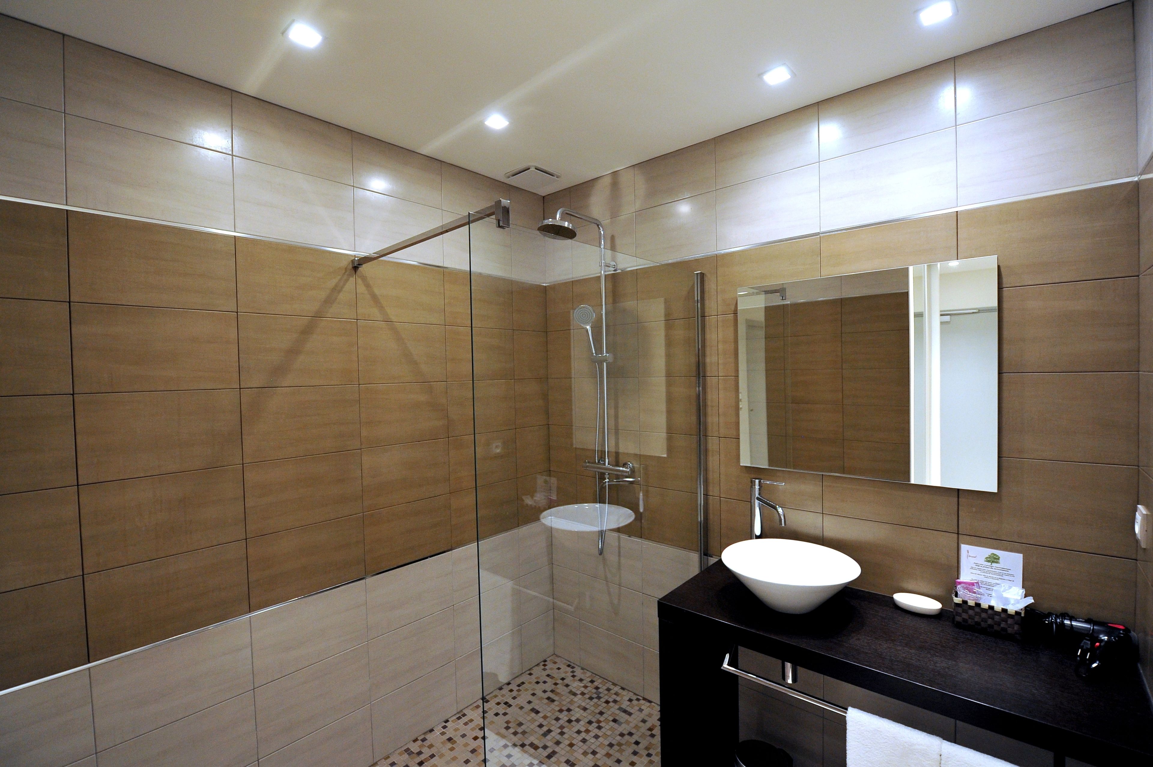 A modern bathroom with a glass-enclosed shower, a white sink, and a large mirror.