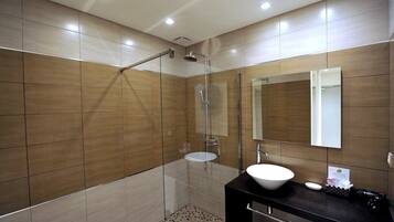 A modern bathroom with a glass-enclosed shower, a white sink, and a large mirror.