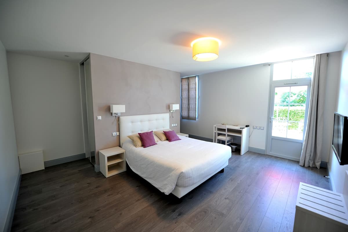 Une chambre d’hôtel moderne avec un grand lit, des tables de chevet, un bureau et une télévision.