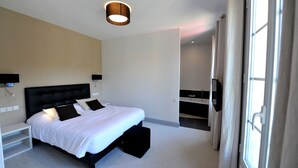 Une chambre d’hôtel moderne avec un grand lit, des tables de chevet, une télévision et une fenêtre avec des rideaux.