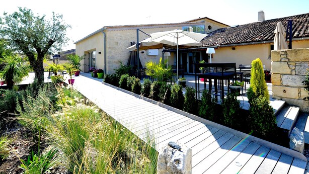 Un bâtiment doté d’un patio, d’un espace extérieur aménagé avec des sièges et d’un chemin.
