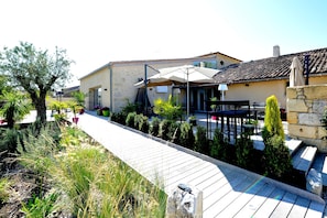 Un bâtiment doté d’un patio, d’un espace extérieur aménagé avec des sièges et d’un chemin.
