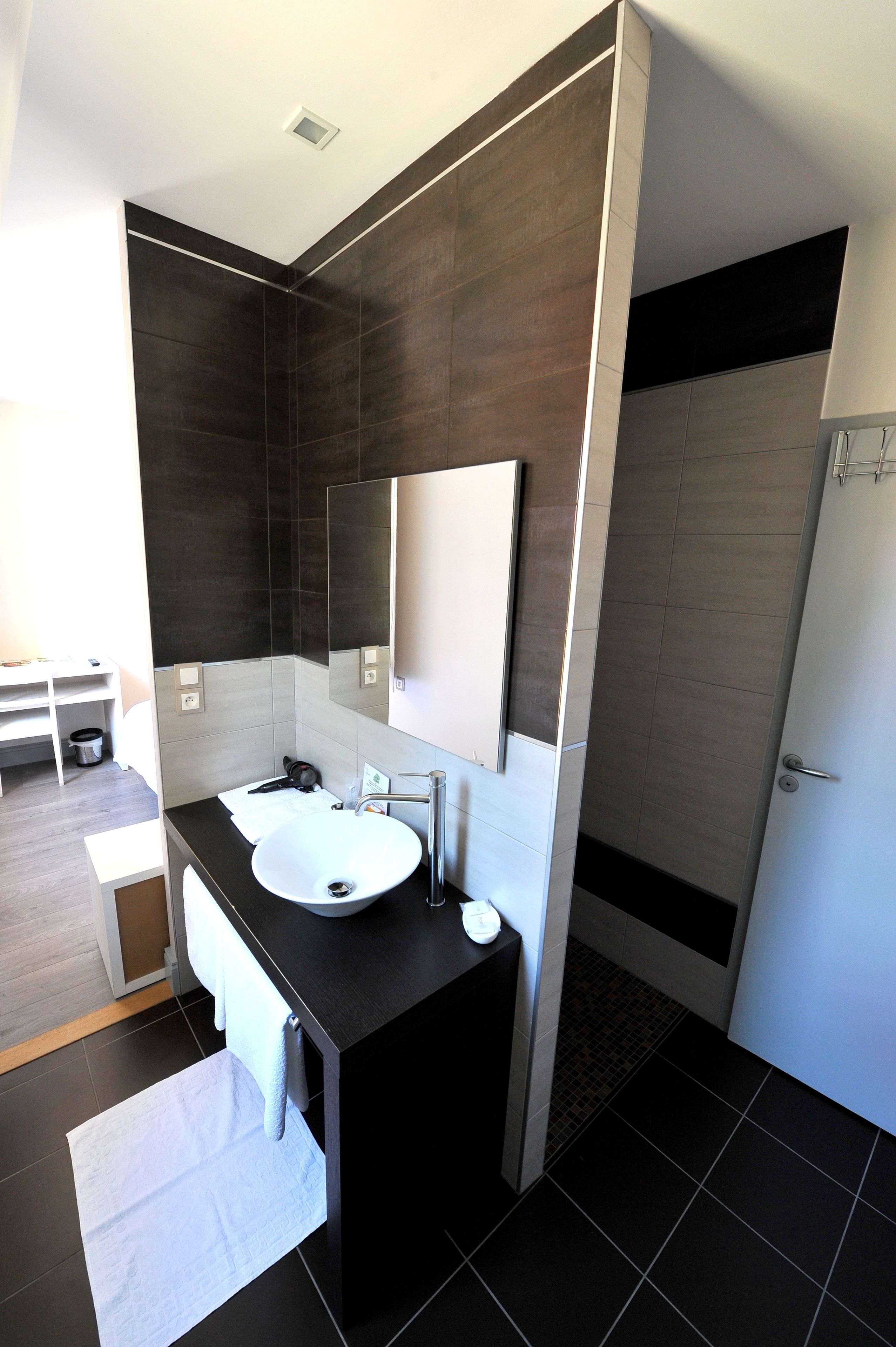 Un bagno moderno con un grande specchio, un lavandino e una zona doccia.