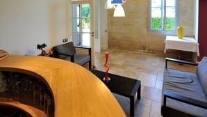 Un intérieur moderne avec une table en bois aux lignes courbes, un canapé noir et un mur en pierre.