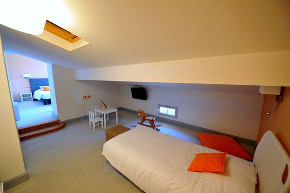 Una habitación de hotel moderna con una cama, un escritorio, un caballo balancín y un televisor en la pared.