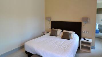 Una habitación de hotel moderna con una cama grande, lámparas de noche, una mesita y una luz en el techo.