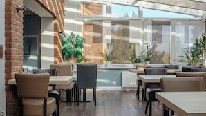 A modern indoor dining area with brick walls, wooden flooring, and multiple tables and chairs. - G&H Hotel Rosengarten (Rosengarten)