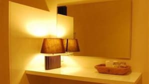A bathroom with a mirror, two lamps, a towel, and a small tray with toiletries. - White House Asoke Sukhumvit 18 (Bangkok)