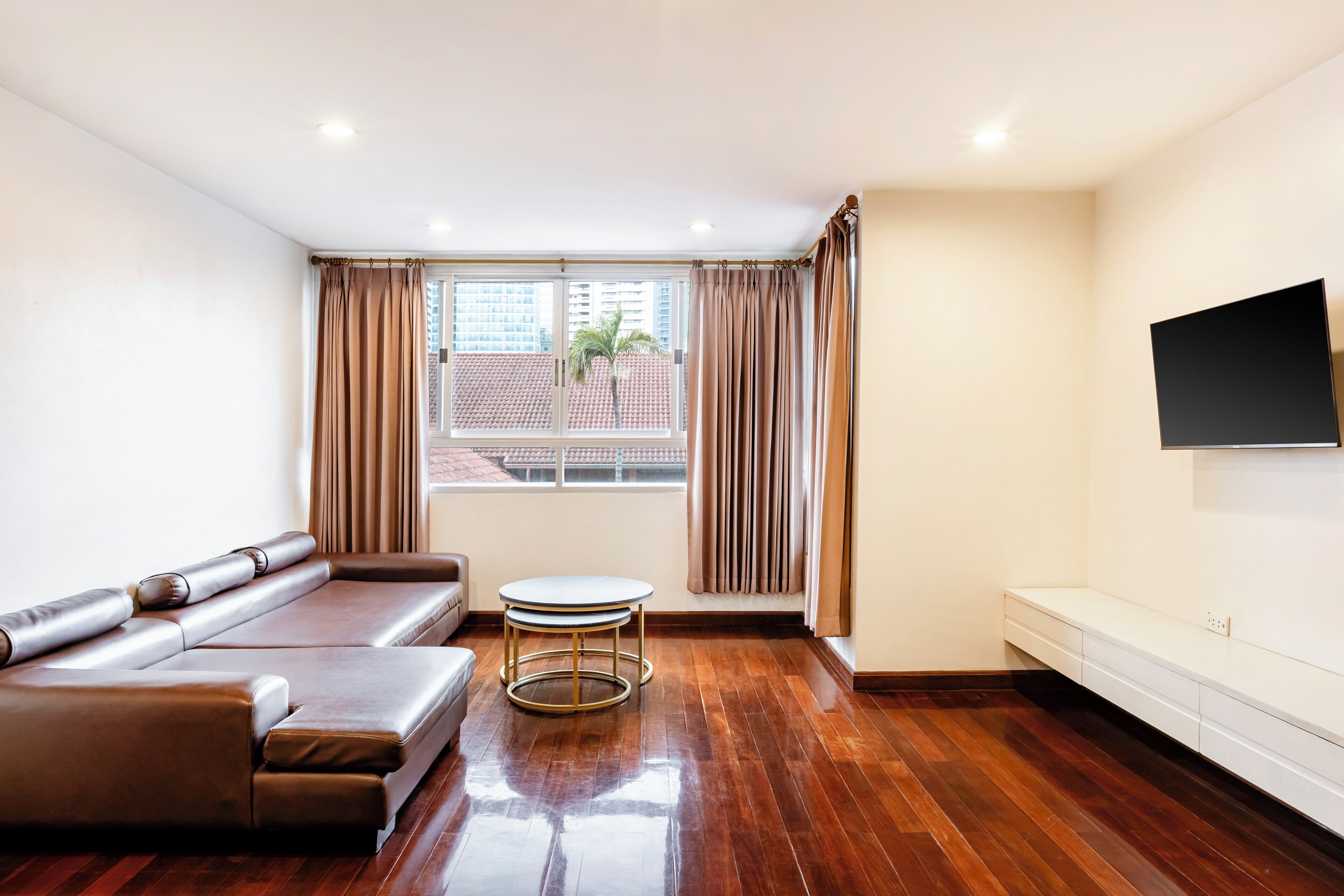 A modern living room with a sofa, a small round table, and a TV mounted on the wall.