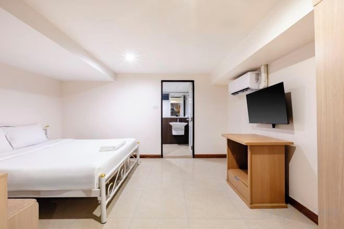 Een hotelkamer met een bed, een aan de muur bevestigde televisie en een houten kast.