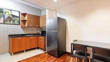 A modern kitchen with wooden cabinets, a black refrigerator, and a dining table with chairs.