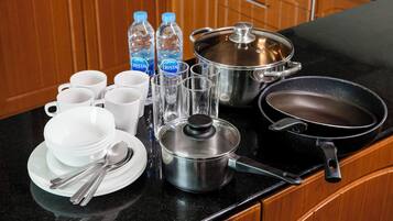 Una encimera de cocina con distintos utensilios, incluyendo una sartén, ollas y tazas.